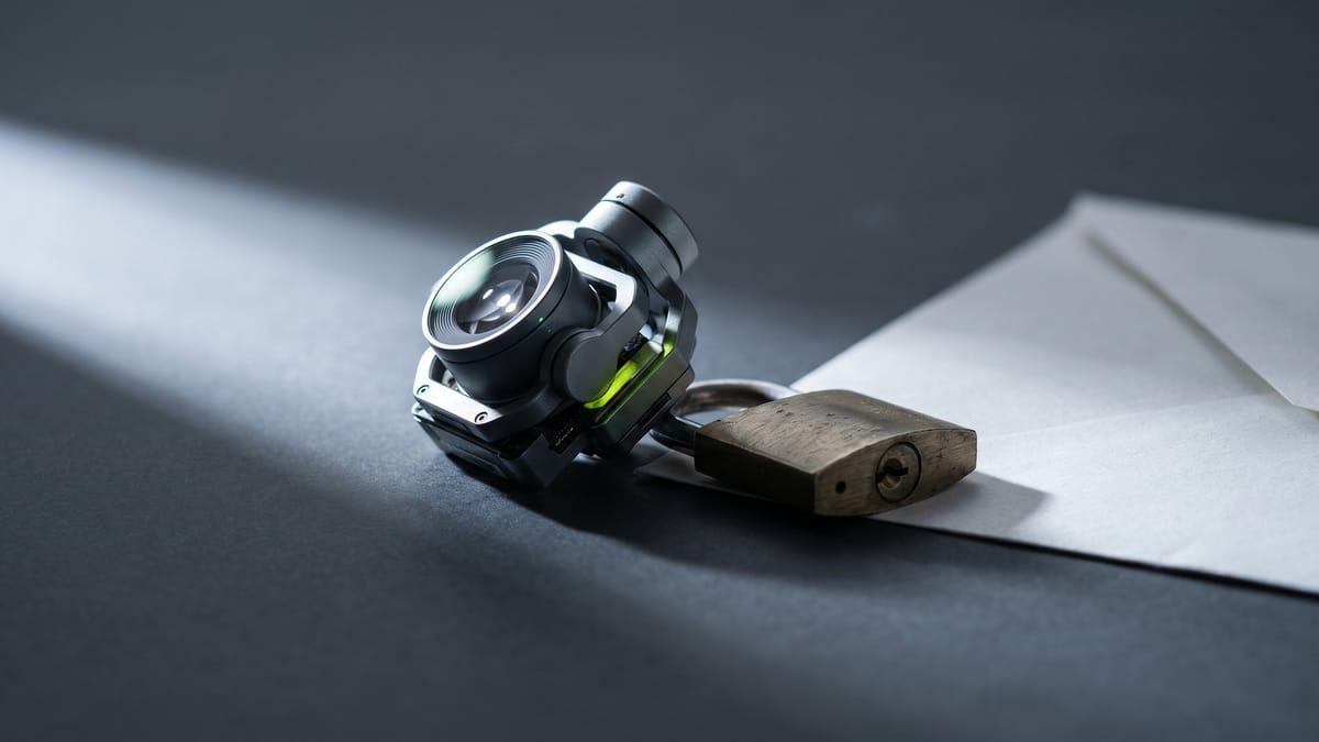 Modulo gimbal con obiettivo, lucchetto e foglio bianco su fondo grafite